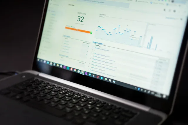 A laptop displaying an analytics dashboard with real-time data tracking and analysis tools. Programmatic advertising audience research, first-party data or panel surveys?