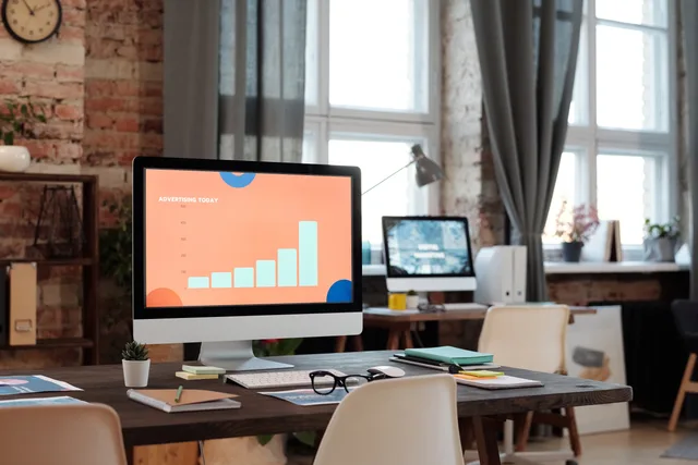 A stylish office setup featuring a computer displaying a graph on advertising trends. Programmatic advertising market entry checklist explained for English agencies