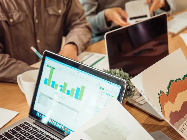 Collaborative business meeting with laptops, graphs, and paperwork. Programmatic advertising measurement without vanity metrics