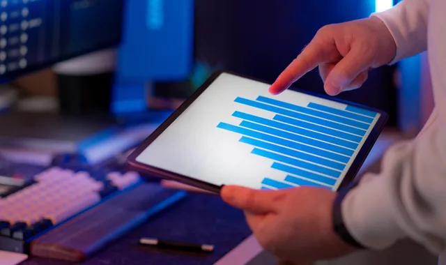 Business professional analyzing bar chart on tablet in office setting, highlighting data insights. Check these programmatic advertising measurement mistakes