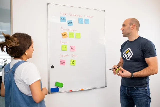 Colleagues brainstorm on project strategy using whiteboard notes at the office. Decisions to settle before building a programmatic advertising reporting dashboard
