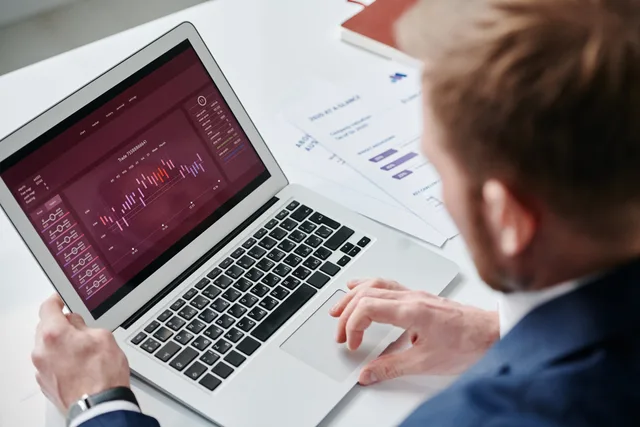 Businessman reviewing data analytics dashboard on laptop in bright office. How to choose programmatic advertising tools and providers